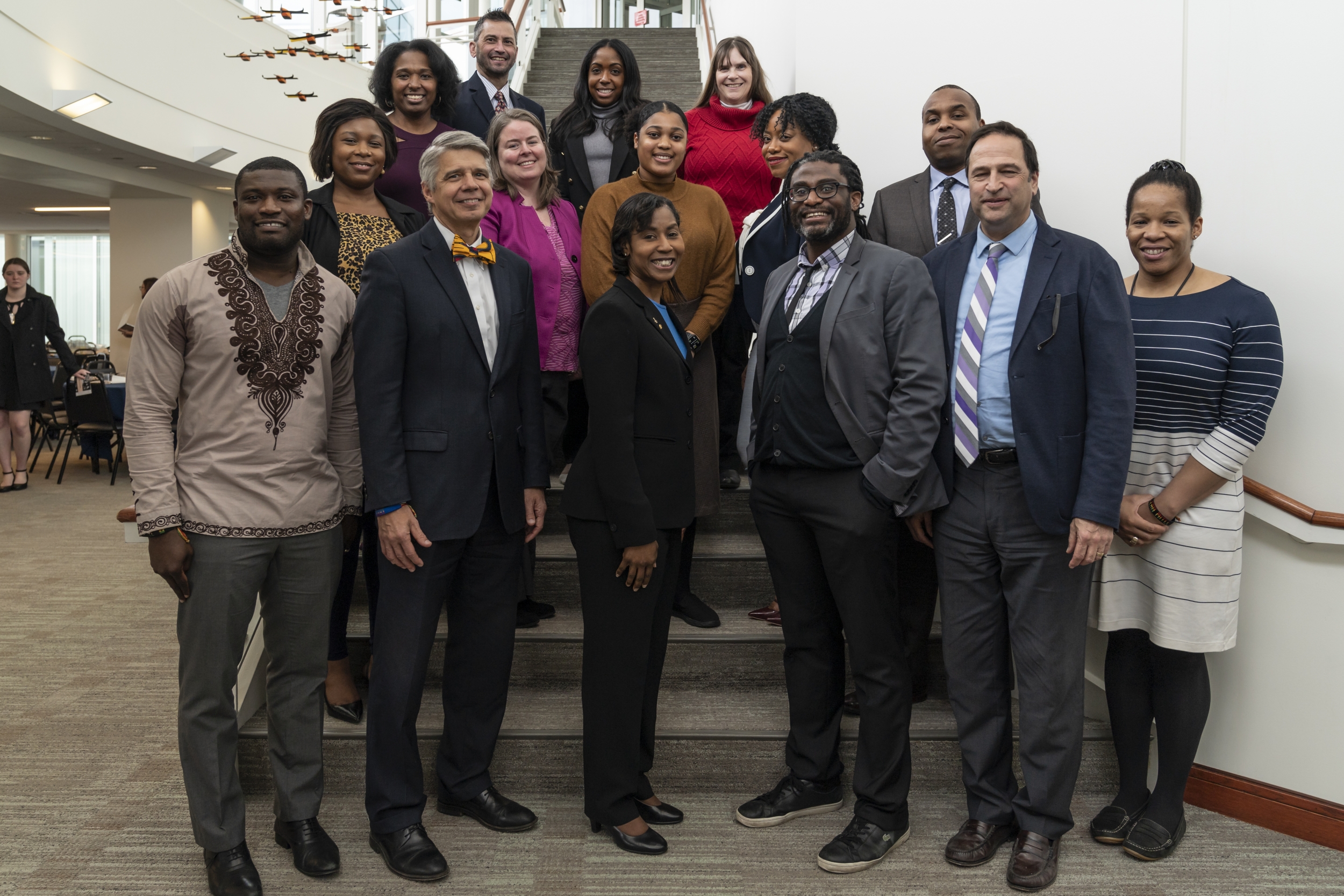 A group of 15 people pose for a photo together on a stairwell