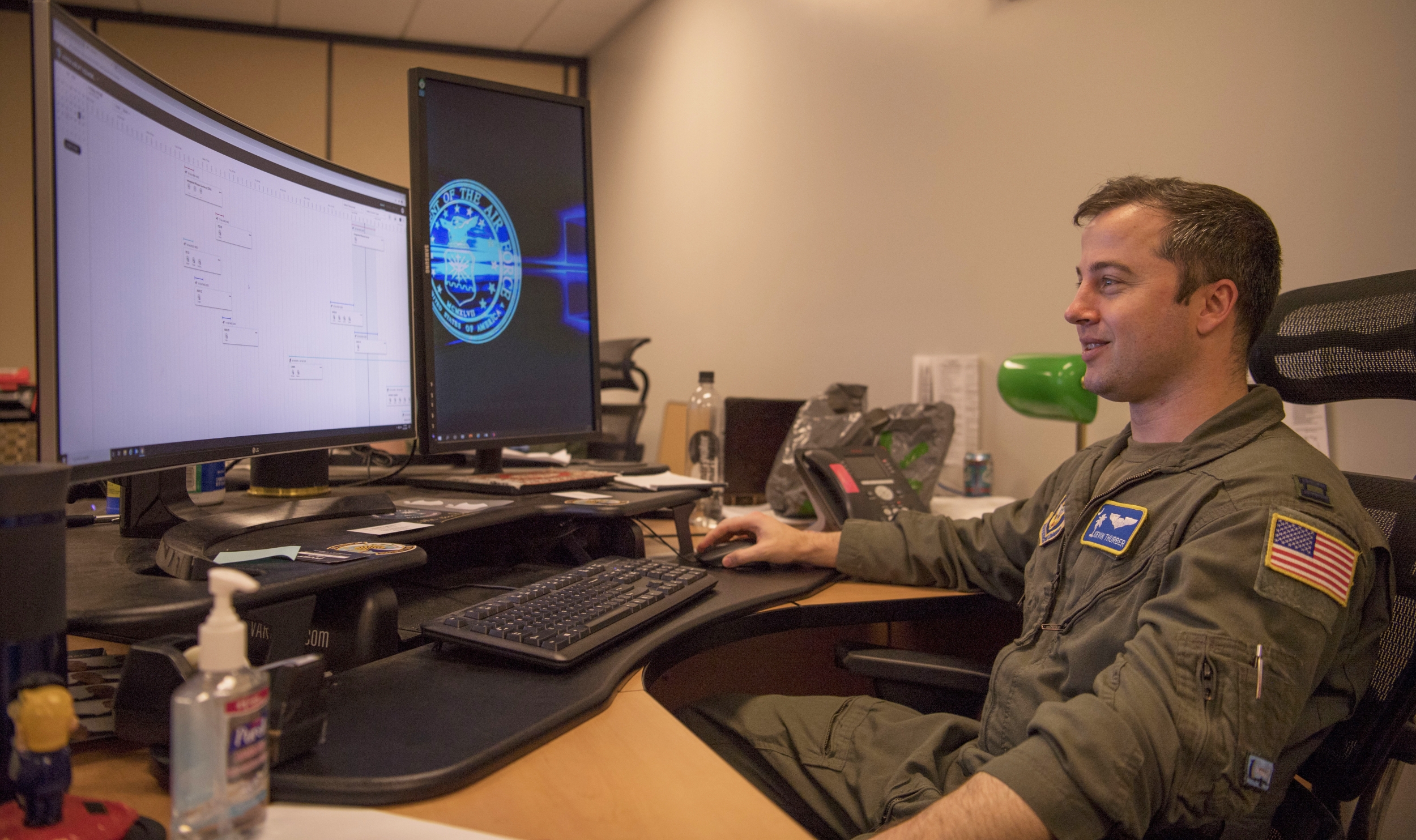 An Air Force pilot sits at a computer screen in an office. 