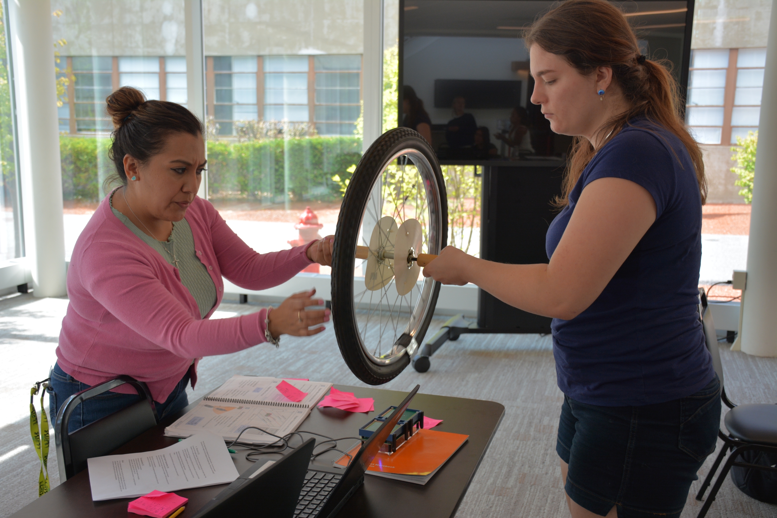 A photo of Esmeralda Hernandez and Liz Raine spinning a wheel above a small radar system they built.