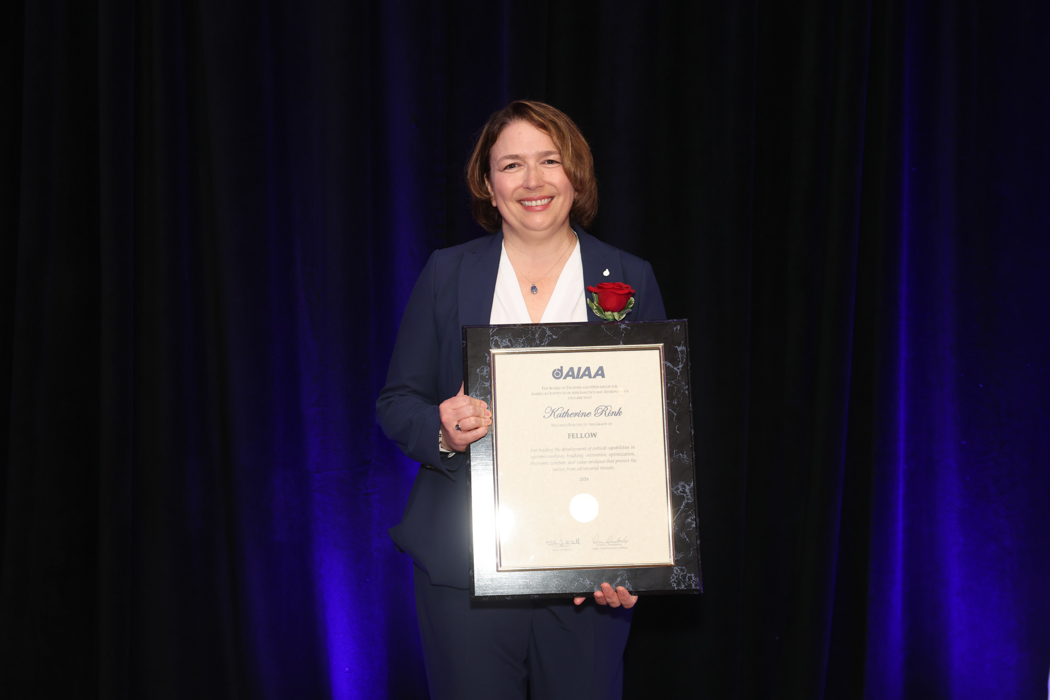 A photograph of Katherine Rink holding a plaque. 