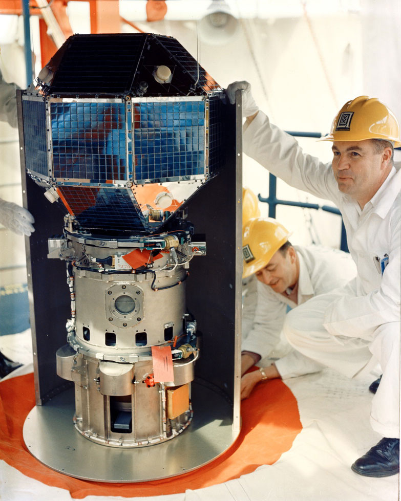 Engineers inspect LES-1 prior to its 1965 launch. The satellite is positioned atop a Titan III rocket on the launch pad at Cape Kennedy, Florida.