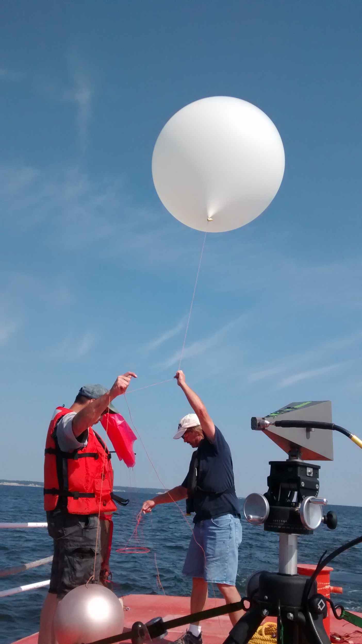 Two people launch a balloon from a ship in the Chesapeake Bay.