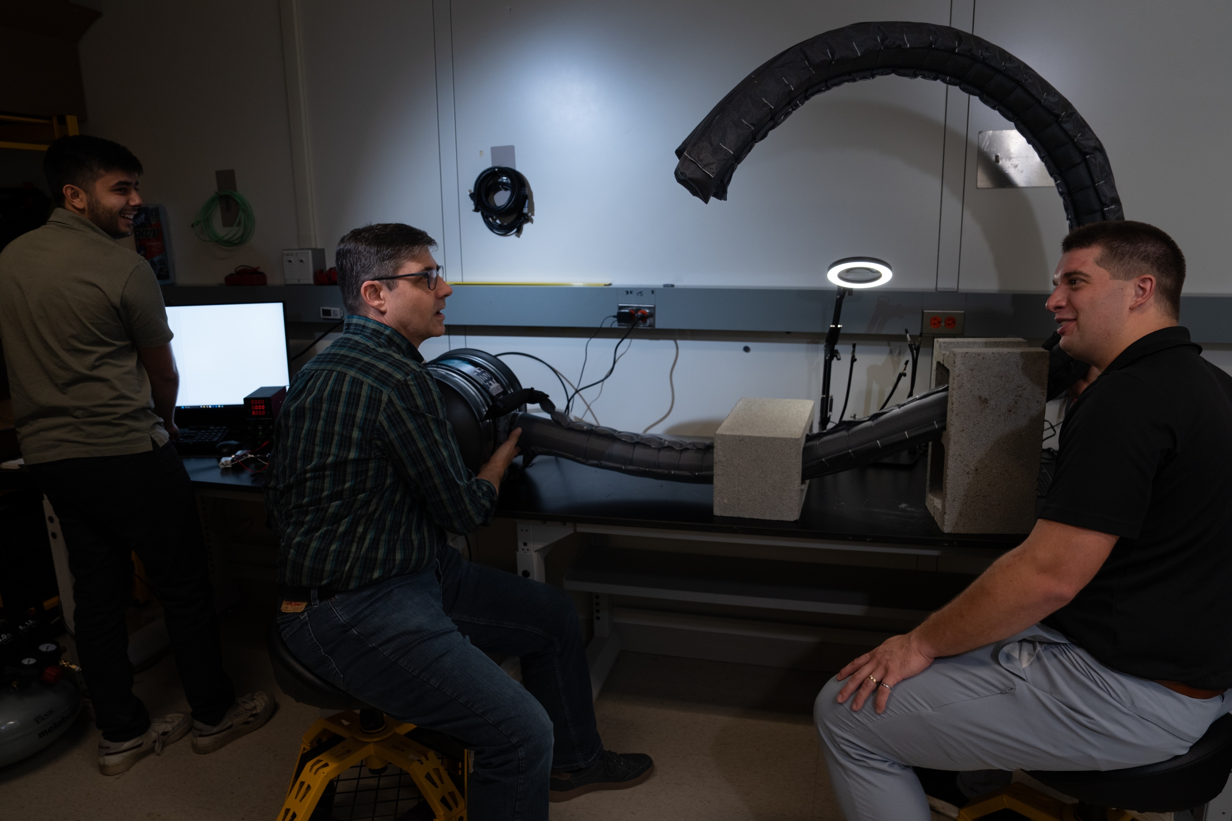 Three project team members test the robot's flexibility in an indoor laboratory setting. 