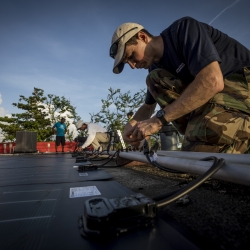 Erik Limpaecher connects cables to solar panels on a roof 