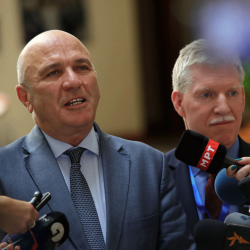 Photo of two men talking into microphones at a press conference 