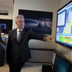 Two researchers stand and point at a screen displaying air traffic control imagery.