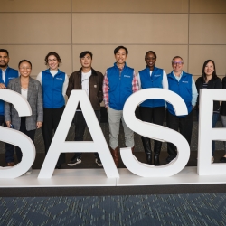 Lincoln Laboratory staff membersstand in front of the SASE logo for a photo at the conference. 